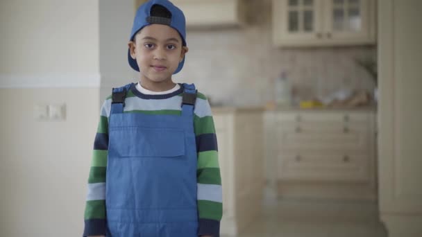 Retrato sorrindo menino afro-americano em um uniforme azul olhando para a câmera . — Vídeo de Stock