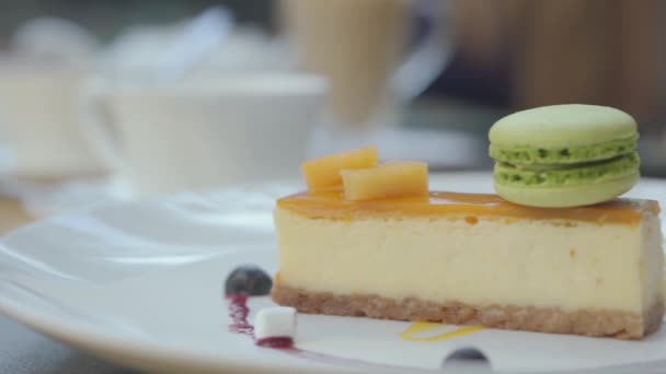 Beautifully served tasty cheesecake with mango and berries and green macaron in restaurant. Close up — Stock Video