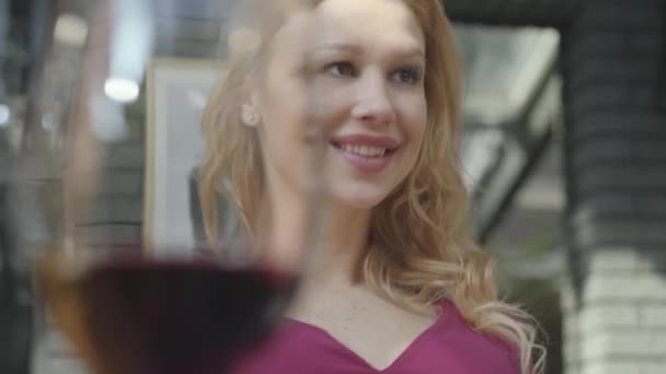 Porträtt elegant kvinna dricker rött vin från det höga glaset i caféet utomhus närbild. Lonely Lady njuter av sin frukost med alkohol. Kameran flyttas till vänster — Stockvideo