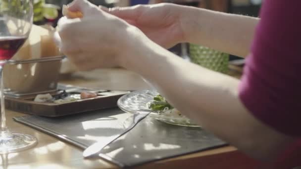 Young woman smearing on bread delicious cheeses and sauces from beautifully served plate in restaurant. Close up. — 비디오