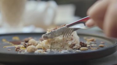 Iştahlı türk kremalı nougat ve fındık kek taze bir parça kesme ile restoran ziyaretçi. Yakın çekim.