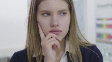 Resmi kıyafetler içinde endişeli üzgün genç bayan Portresi uzağa bakıyor ve kamera, onun sorunu yakından düşünme. Uzun saçlı kadın ofiste. Çalışma süreci
