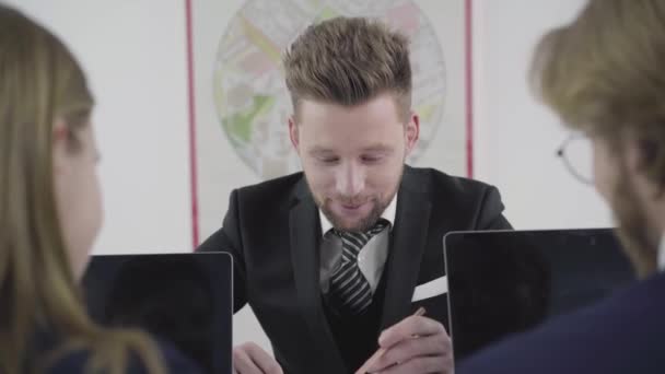 Portret drie collega's werken aan de tafel samen, man en vrouw zijn in de buurt van notebooks. Mensen die betrokken zijn bij het werkproces op kantoor. Werkplek. Kantoorruimte. — Stockvideo