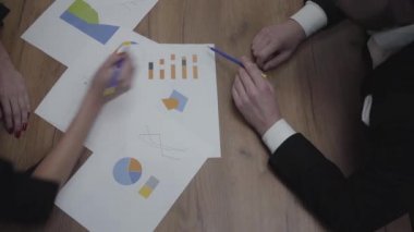 Büyüme oranlarını ve eğilimleri analiz eden tanınmayan iş adamlarıyla grafik veri şablonları tablosunun çekimi. Yukarıda görüş. Işyeri. Ofis alanı.