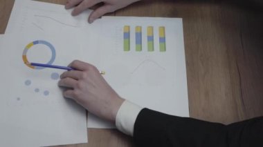 Büyüme oranlarını ve eğilimleri analiz eden tanınmayan iş adamlarıyla grafik veri şablonları tablosunun çekimi. Yukarıda görüş. Işyeri. Ofis alanı.