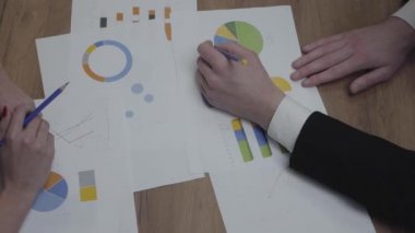 Büyüme oranlarını ve eğilimleri analiz eden iş adamlarıyla grafik veri şablonları tablosunun çekimi. Yukarıda görüş. Işyeri. Ofis alanı.