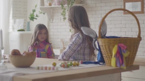 Young mother and her preteen daughter talking on the kitchen. Woman listening to her emotional girl, caress her hair and shoulder. Easter eggs are on the table. Relationship mothers and daughters. — 비디오