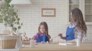 Küçük bir kız küçük bir fırça kullanarak annesi ile yumurta boyama. Mutlu bir aile. Paskalya'nın hazırlanması.