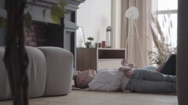Çocuk odasında yerde yatan iki sevimli genç erkek konuşuyor, paylaşıyor, iletişim kuruyor. Kardeş sevgisi kavramı. Mutlu aile