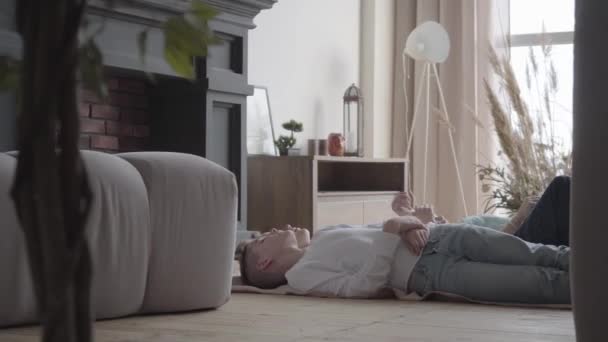 Dos chicos adolescentes lindos tumbados en el suelo en la habitación de los niños hablando, compartiendo, comunicándose. Concepto de hermano amor. Familia feliz — Vídeos de Stock