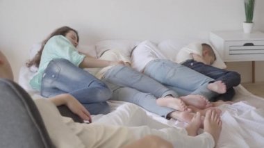 Portre genç anne onun genç oğulları ile birlikte büyük yatakta uyku. Sandalyede oturan bir çocuk. Mutlu sevgi dolu aile konsepti. Birçok çocuk ile aile içinde sessiz saat