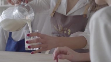 Tanınmayan kadın sütü bardağa döker ve oğluna verir. Önlükteki kadın çocukları önemsiyor. Sağlıklı yaşam tarzı kavramı