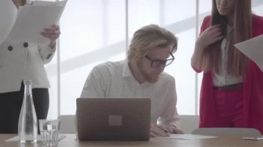 Portre başarılı emin işadamı gözlüklü açık ve konforlu bir ofiste oturan netbook ile masanın başında meslektaşlarının kendisine getirdiği belgeleri imzalıyor. Resmi giyim iki kız