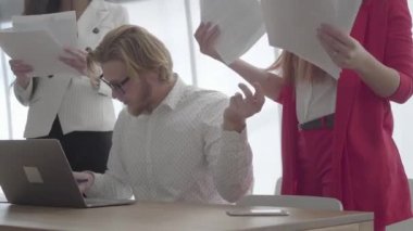 Portre başarılı meşgul işadamı gözlük lüzumlu bir ofiste netbook ile masanın içinde oturan iş arkadaşları ona getirdiği belgeleri imzalıyor. Resmi giyim iki kız ayakta