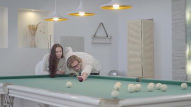 Başarılı sarışın sakallı adam bilardo oynamak için kız arkadaşı öğretir. Beyaz gömlekli kendine güvenen adam, bilardo oynamayı zarif takım elbiseli kadına anlatıyor. Bilardo spor konsepti