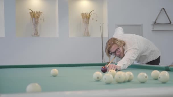 Blond bearded man playing pool, billiards in light room. Confident player hits the ball with a cue. American pool billiard. Pool billiard game. Billiard sport concept — Stock Video