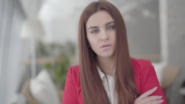 Portre güzel iş kadını kameraya bakarak hafif rahat bir ofiste ayakta. Ofis alanında işyerinde başarılı kendine güvenen kız.