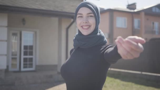 Portret van de onafhankelijke jonge moslim vrouw glimlachend en flirten dragen traditionele hoofddoek. Schattig meisje nemen operator hand buitenshuis. — Stockvideo