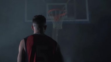 Topu sepete koyan kaslı güçlü bir adamın arkası. Basketbolcu.