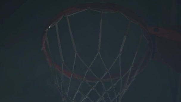 Primo piano mani del giocatore di basket lancia la palla nel cestino sullo sfondo scuro. Giovane giocatore di basket in azione. Concetto di sport — Video Stock