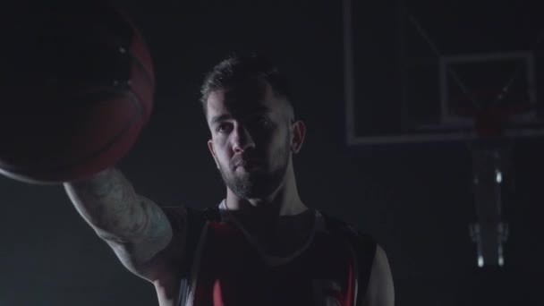 Retrato de un joven musculoso fuerte sosteniendo una pelota en la mano. Fondo oscuro con humo . — Vídeo de stock