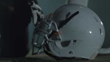 Amerikan futbolcunun yakın elleri, maçtan önce kaskının üzerinde yatan eldivenli. Spor kavramı, zafer