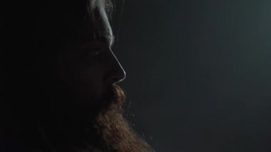 Uzun saçlı ve sakallı ve uzun saçlı amerikalı futbolcunun yakın portresi, oyun dan önce miğferini yüzüne yakın tutarak kapatın. Spor kavramı, zafer, erkeklik