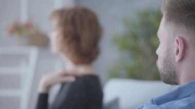Yakın genç sakallı adam arka planda adam yanında oturan saçlarına dokunan yaşlı bir olgun kadının bulanık rakam bakarak. Yaşlı kadın ve genç erkek arasındaki ilişki