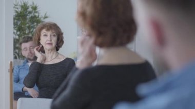 Oldukça kıdemli olgun kadın aynaya onun yansıması bakarak, mavi gömlekli genç adamın önünde oturan saçlarına dokunarak. Yaşlı kadın ve genç adam arasındaki ilişki. Yaş farkı