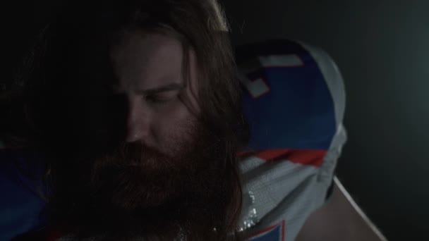 Close up retrato de um jogador de futebol americano barbudo com cabelos longos e barba em equipamentos esportivos gritando olhando para a câmera . — Vídeo de Stock