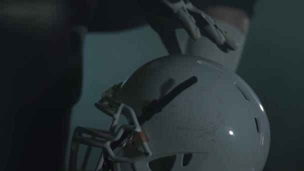 Cierre las manos del jugador de fútbol americano con guantes acostados en su casco antes de cerrar el juego. Concepto de deporte, victoria — Vídeos de Stock
