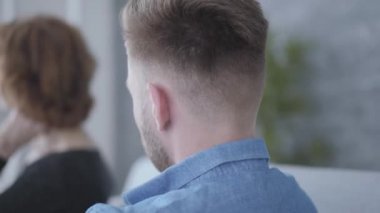 Yakın portre genç sakallı adam arka planda adam yanında oturan saçlarına dokunan üst düzey olgun bir kadının bulanık rakam bakarak. Yaşlı kadın ve genç erkek arasındaki ilişki