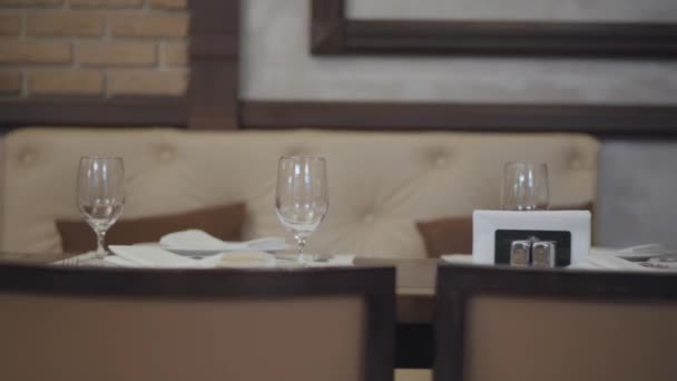 Ampty glasses, plates, fork, knife served for dinner in restaurant with cozy interior. Table serving. — Stock Video