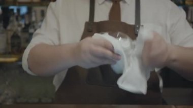 Önlükte tanınmayan barmen havluyla şarap bardağını siler. Barda birçok bardak cam bulunmaktadır. Modern restoranda çalışmaya hazırlık