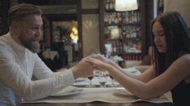 Glamour esmer kadın ve yakışıklı sakallı sarışın adam birbirlerinin önünde masada oturuyor. Kız arkadaşına güzel sözler söyleyen adam elini öpüyor. Sevimli çiftin bir randevusu var.