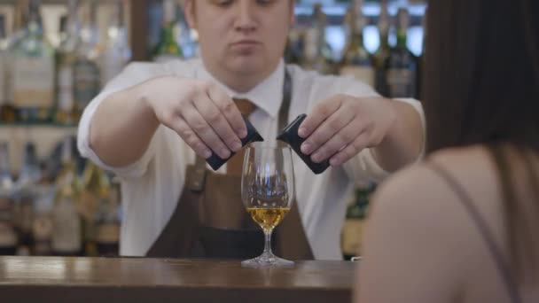 Den oigenkännliga Brunette kvinnan sitter vid bardisken. Plump bartender hälla två delar av espresso i glaset med alkohol för kvinnliga besökare — Stockvideo