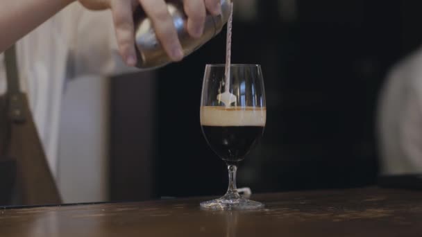 男性调酒师使用特殊工具向女性访客倒入玻璃杯中，将牛奶倒入酒精和咖啡中，使其停留在液体顶部。准备、服务理念 — 图库视频影像