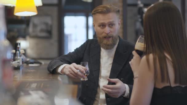 Симпатичная брюнетка и белокурый бородатый мужчина, сидящий за барной стойкой. Концепция ночного образа жизни. У милой пары свидание. . — стоковое видео