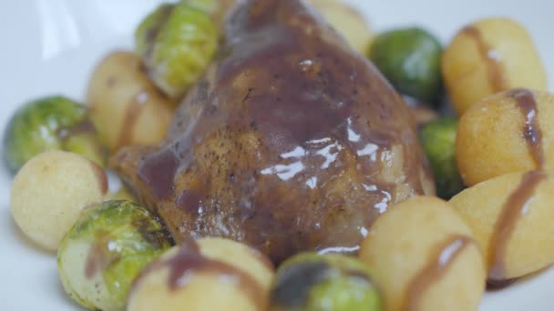 Вкусное мясо утки с соусом сверху, лежащим на тарелке со свежеобжаренными брюссельскими капустой и сырными шариками. Концепция приготовления здорового питания — стоковое видео