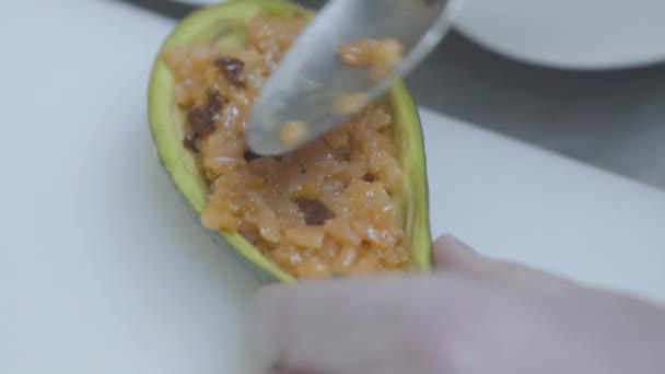 Aguacate de relleno de manos masculinas con trozos de pescado rojo salmón — Vídeos de Stock