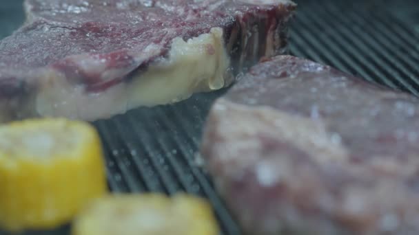 Close-up van twee grote inzetten zijn grillen op de hitte met maïs. — Stockvideo