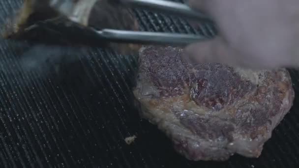 Gros plan de deux morceaux de viande crue dans la cuisine du restaurant. Chef transforme la viande à l'aide de pinces. Le chef préparant une cuisine savoureuse . — Video