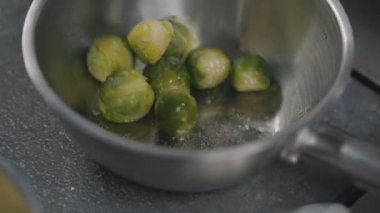 Pişirme yüzeyinde yakın çekim tavada taze brüksel lahanası. Tavada zeytinyağı ile kavrulan lahanalar kaşıkla karıştırılır. Vejetaryen mutfağı