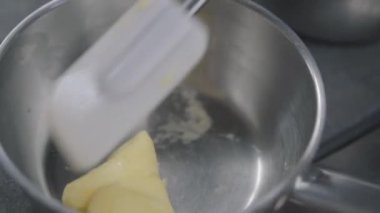 Tavada paslanmış bir parça chees mutfakta yakın. Aşçı kauçuk spatula ile gıda karıştırma. Gıda hazırlama konsepti