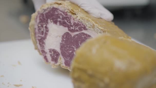 Chef mano sosteniendo carne congelada cubierta con cubierta amarilla acostado en la mesa de cerca. El cocinero prepara comida en la cocina del restaurante. Preparación de plato de carne — Vídeos de Stock