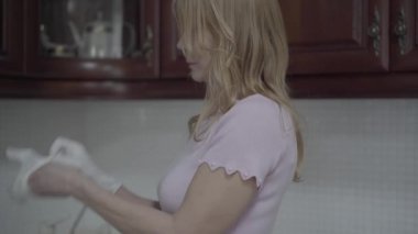 Bulaşık eldiveni giyen güzel sarışın kadın ve bulaşıkyıkamaya başlayın