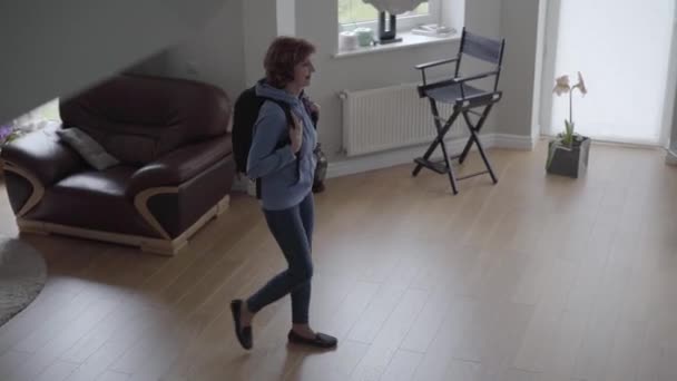 Slim donna camminare all'interno di una bella casa con comodo zaino sul retro e bionda bella donna incontrarla con grande sorriso e fissare borsa sul retro. Vista dall'alto — Video Stock