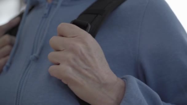 Een zwarte comfortabele rugzak op de rug close-up. Dames hand bevestigingstas op rug — Stockvideo