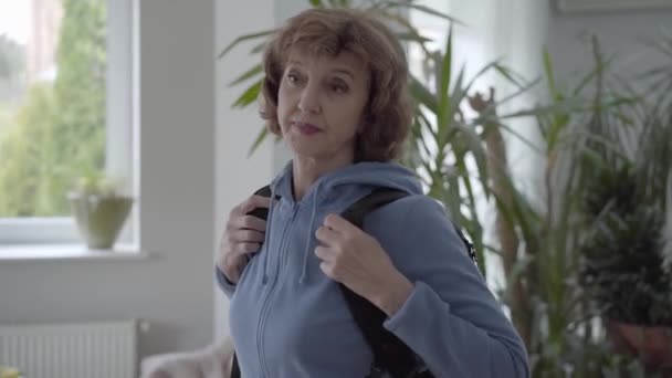 Mulher madura em azul com capuz fixação preto mochila confortável em suas costas — Vídeo de Stock