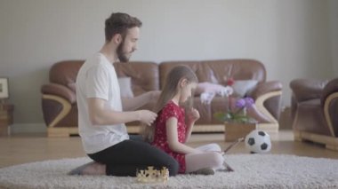 Genç ve yakışıklı babası, sevimli, uzun saçlı kızlarının kafasını taca takmış ve o da mutlu.